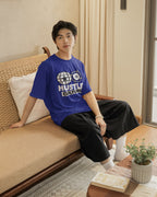 Person wearing a blue t-shirt with text sitting on a couch in a living room.