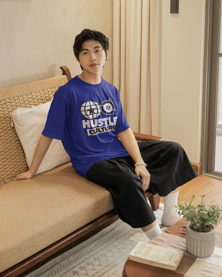 Person wearing a blue t-shirt with text sitting on a couch in a living room.