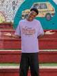 Person wearing a purple t-shirt with text, standing in front of a colorful mural.