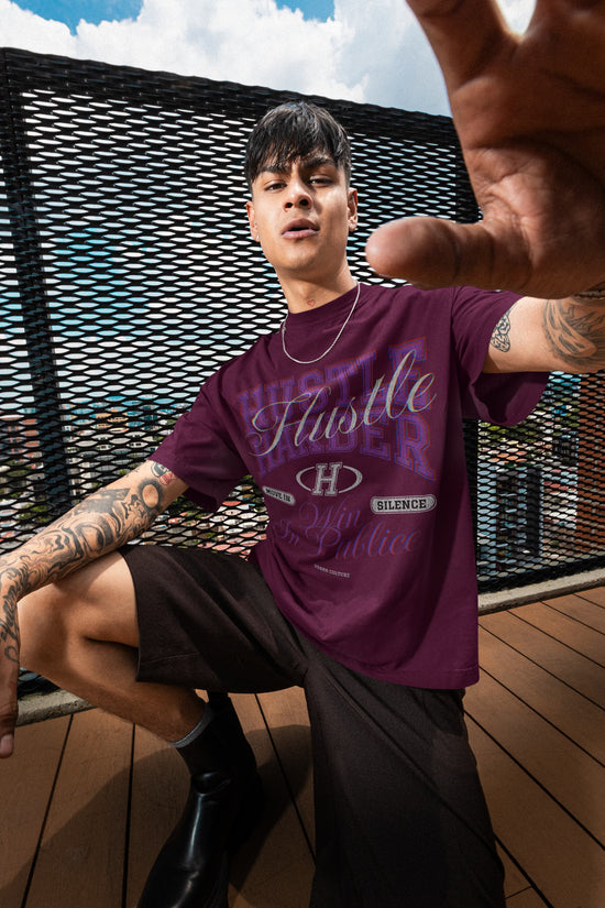 Person wearing a purple t-shirt with text and graphics, sitting on a wooden deck.