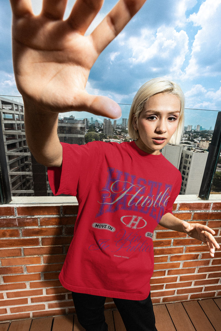 Person wearing a red t-shirt with visible branding, standing on a rooftop with cityscape in the background.