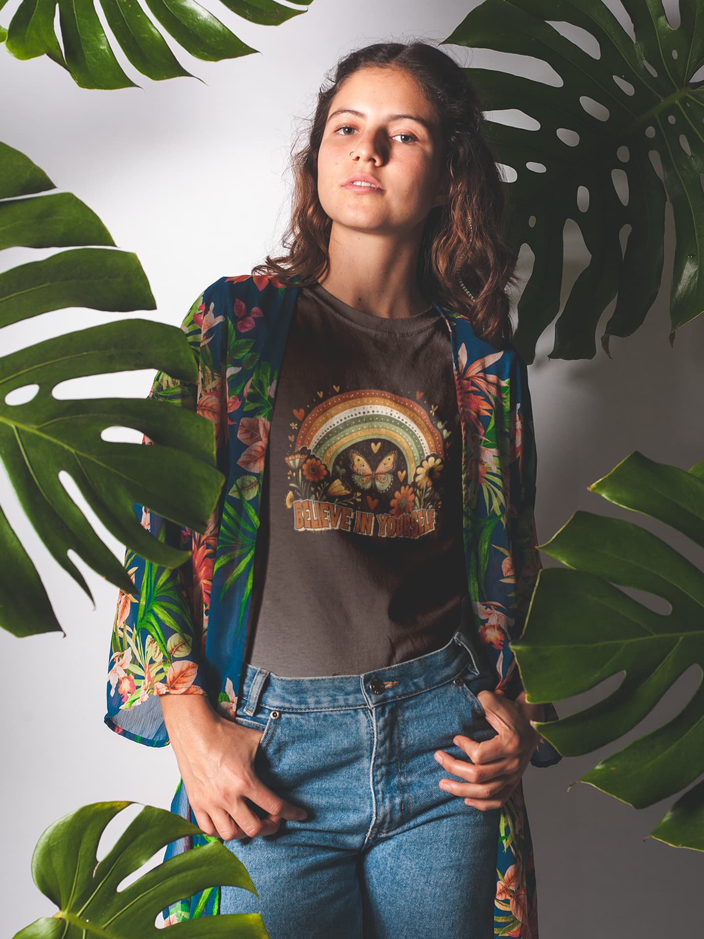 Woman wearing a colorful jacket and graphic t-shirt with leaves in the background