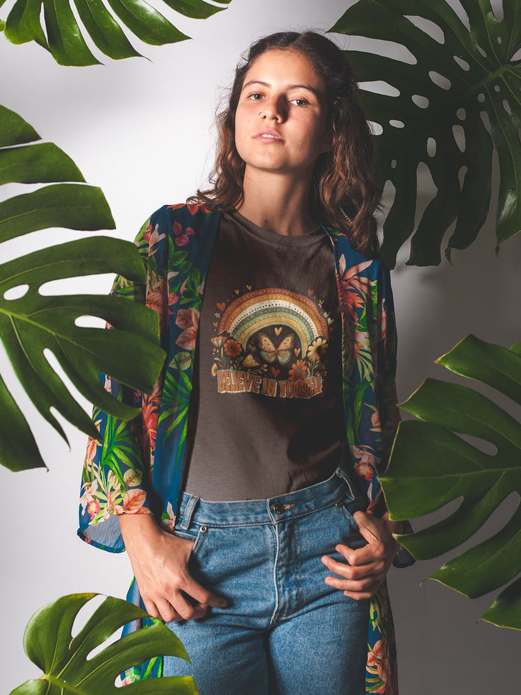 Woman wearing a colorful jacket and graphic t-shirt with leaves in the background