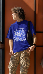 Person wearing a blue t-shirt with 'FEAR NOTHING' text against an orange wall.