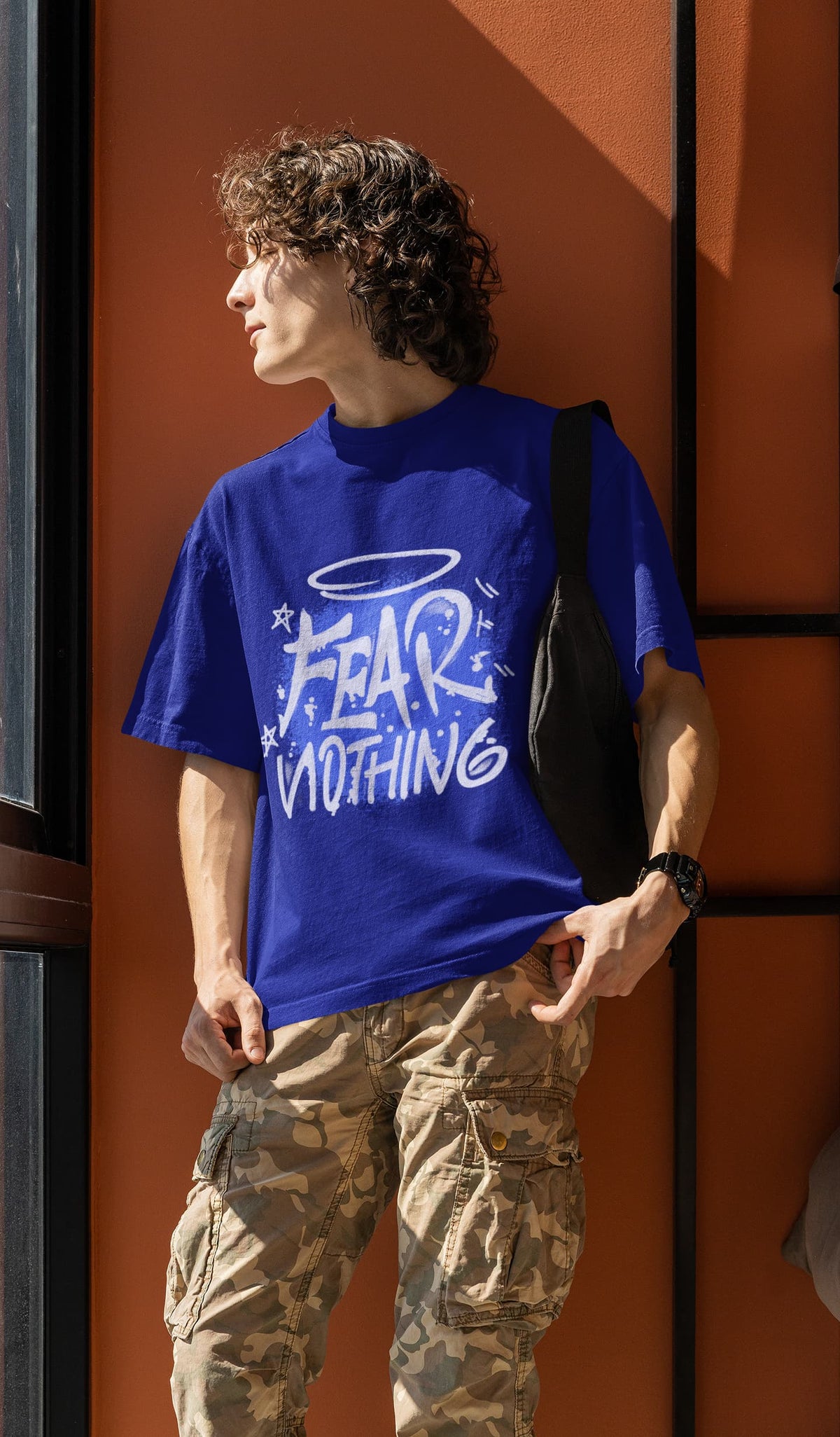 Person wearing a blue t-shirt with 'FEAR NOTHING' text against an orange wall.