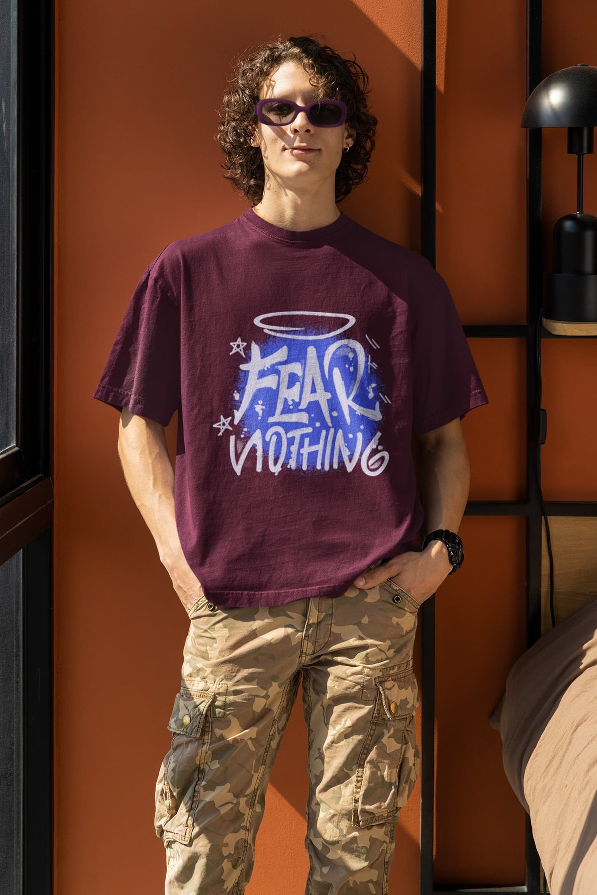 Person wearing a purple t-shirt with 'Fear & Nothing' graphic design against an orange wall.