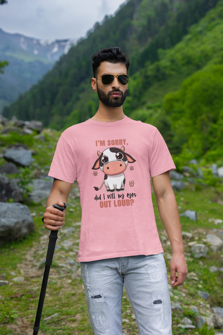 Man wearing a pink t-shirt with a cow graphic and text in a mountainous landscape
