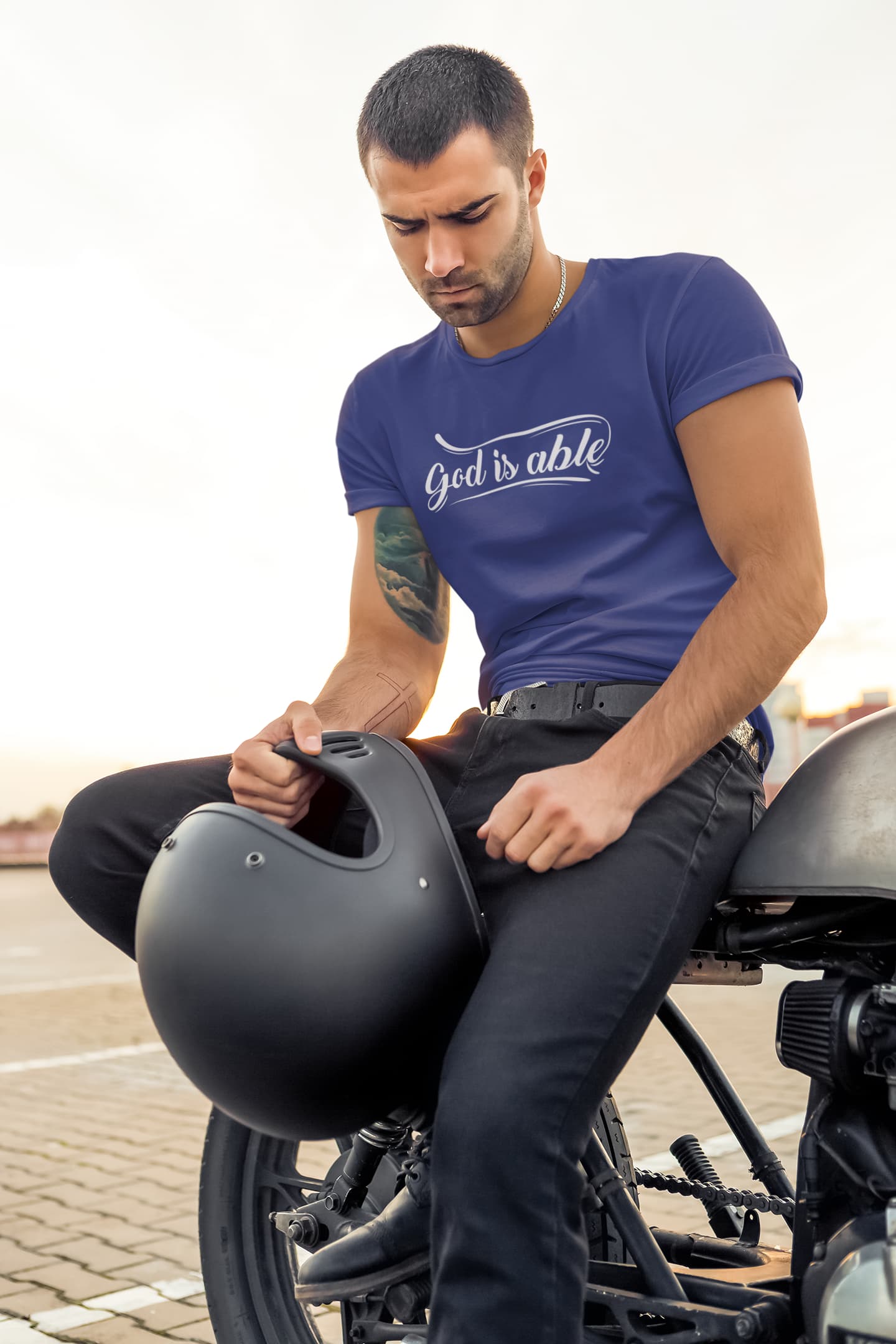 Man sitting on a motorcycle wearing a blue t-shirt with &
