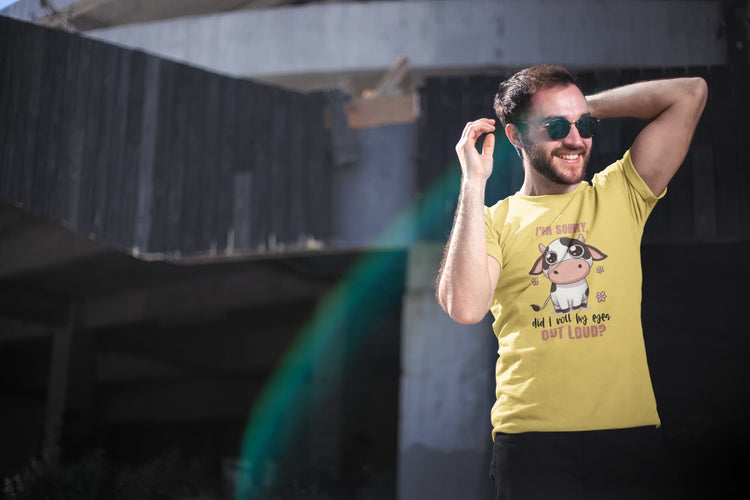 Man wearing a yellow t-shirt with a cow graphic and text, standing outdoors.