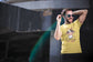 Man wearing a yellow t-shirt with a cow graphic and text, standing outdoors.