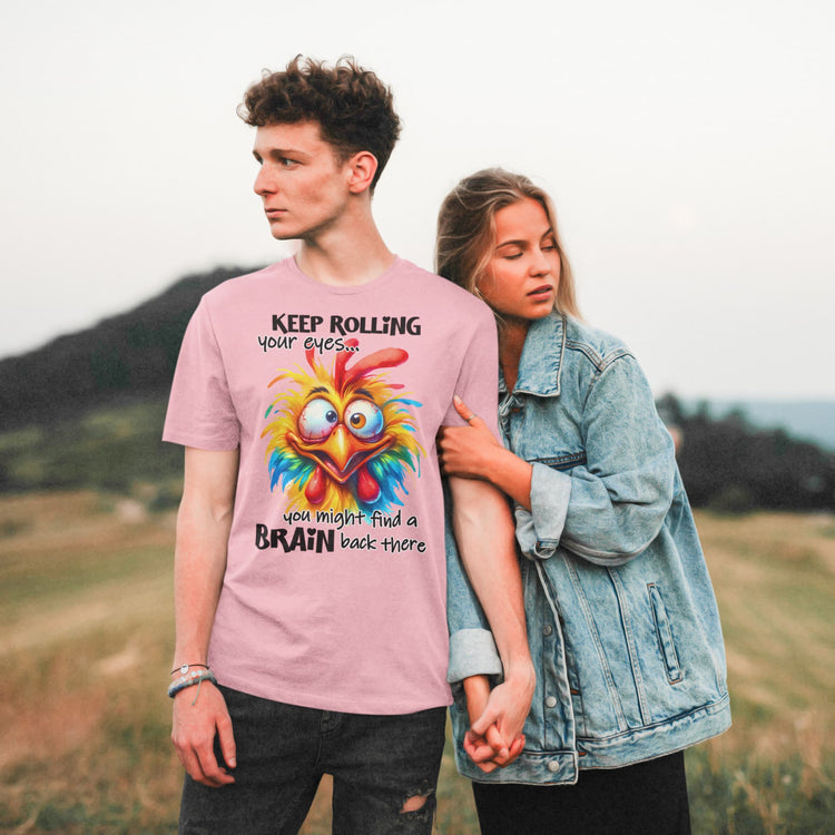 Two people standing in a field with one wearing a pink t-shirt with a colorful graphic and text.