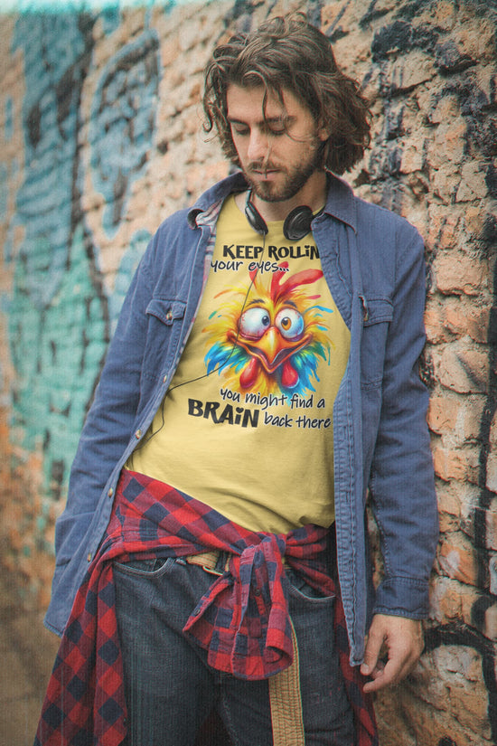 Man wearing a colorful t-shirt with a cartoon rooster design against a textured wall.