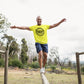 Man balancing on a log outdoors wearing a yellow &