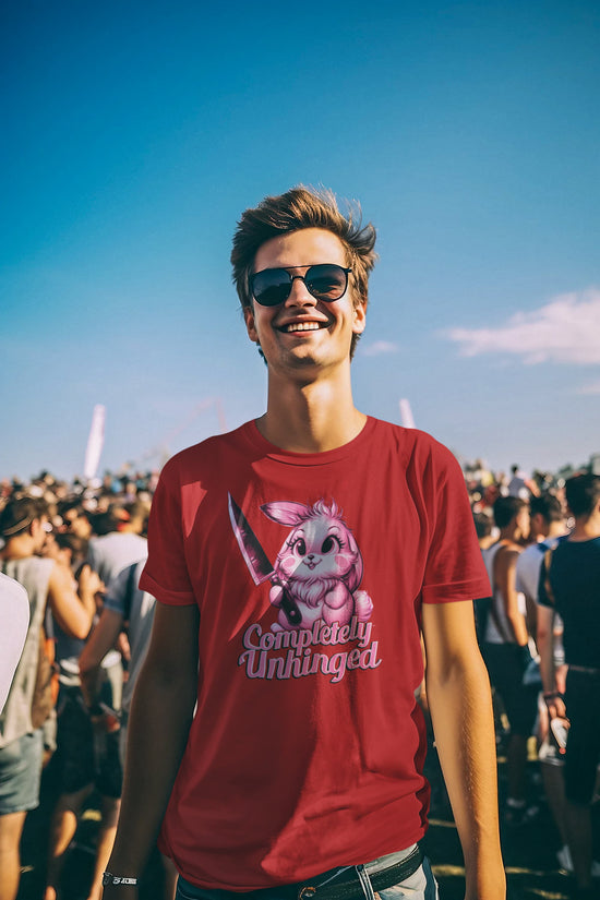 Man wearing a red t-shirt with a graphic design and sunglasses, standing outdoors with a blue sky and people in the background.