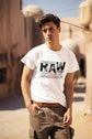 Man wearing a white t-shirt with text standing outdoors.