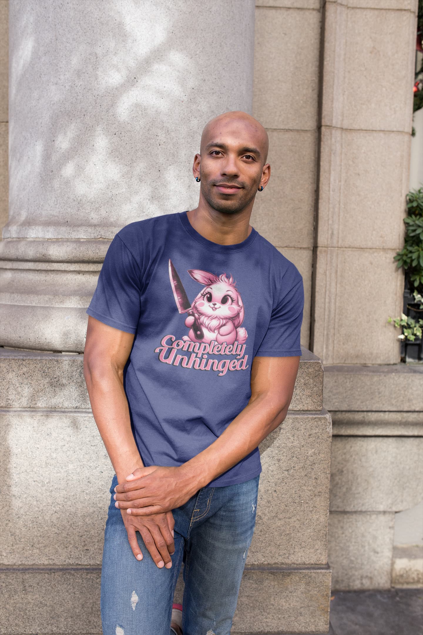 Man wearing a blue t-shirt with a graphic design standing outdoors.