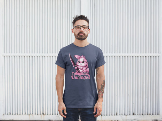 Man wearing a t-shirt with a graphic design and text standing against a white wall.