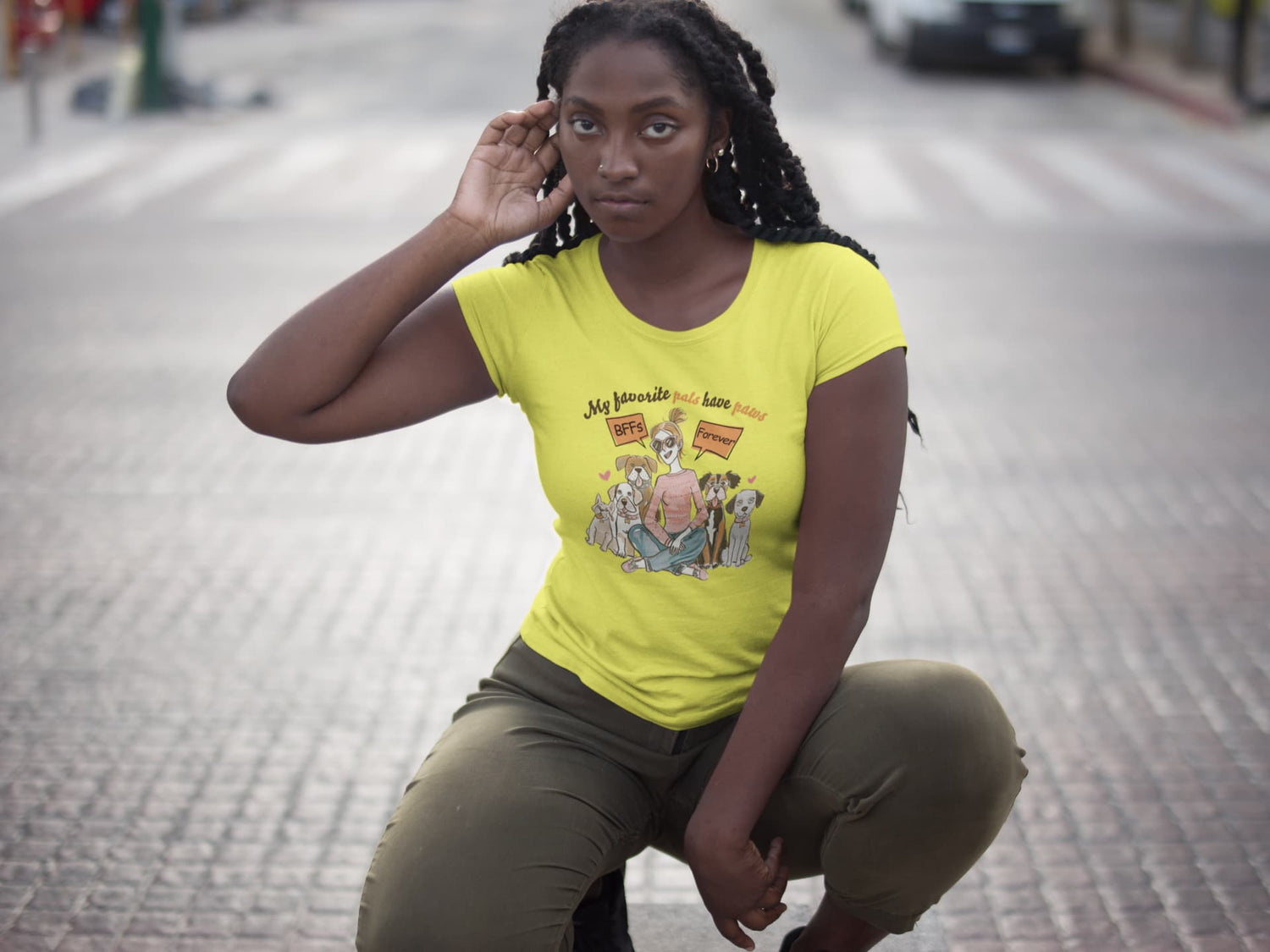 Woman wearing a yellow t-shirt with a graphic design on a city street.