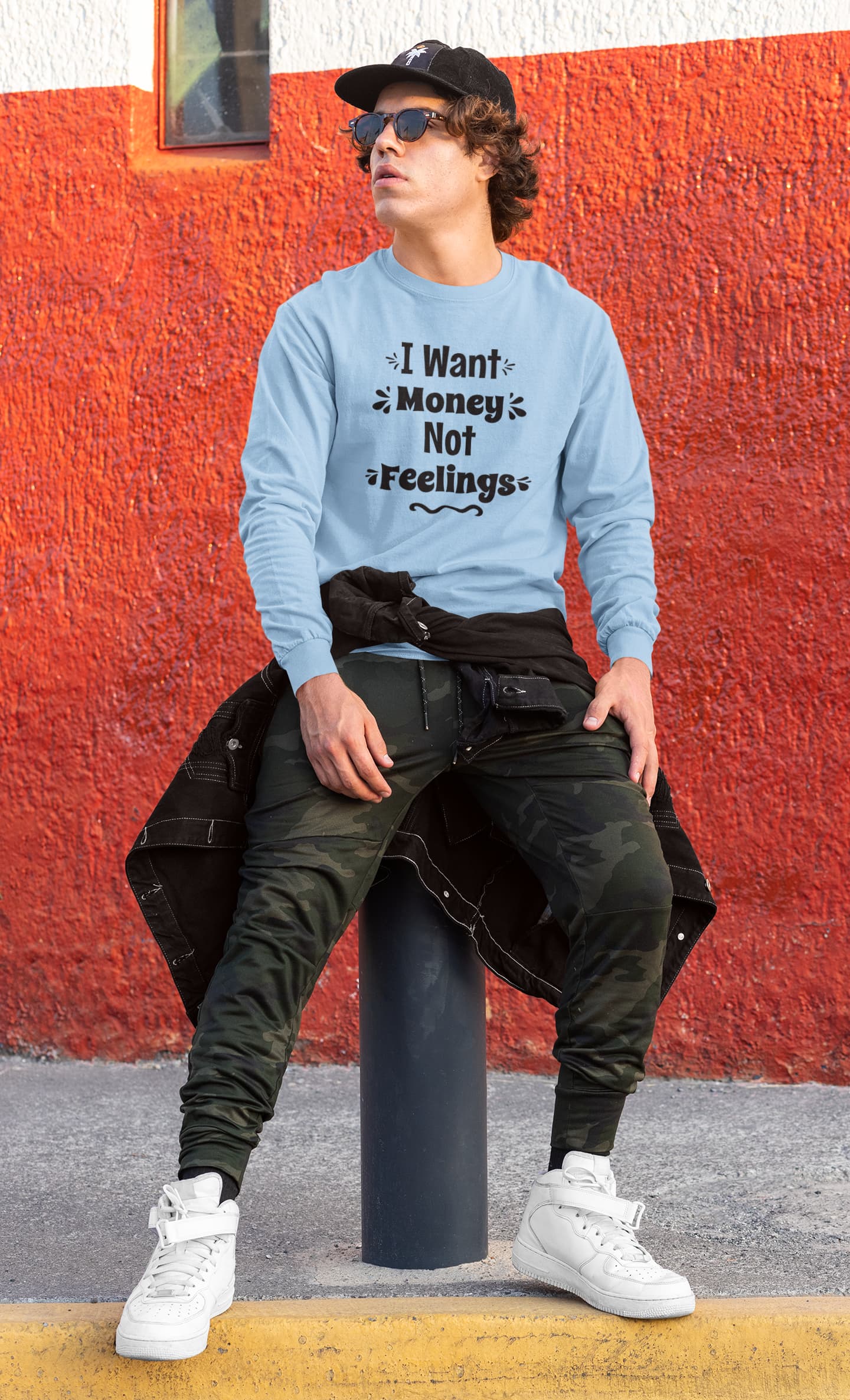 Person wearing a light blue sweatshirt with text, sitting against a red wall.