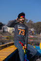 Man sitting on a boat with colorful flags, wearing a dark gray sweatshirt with &