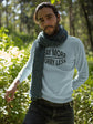 Person wearing a white sweatshirt with text and a blue scarf in a forest setting