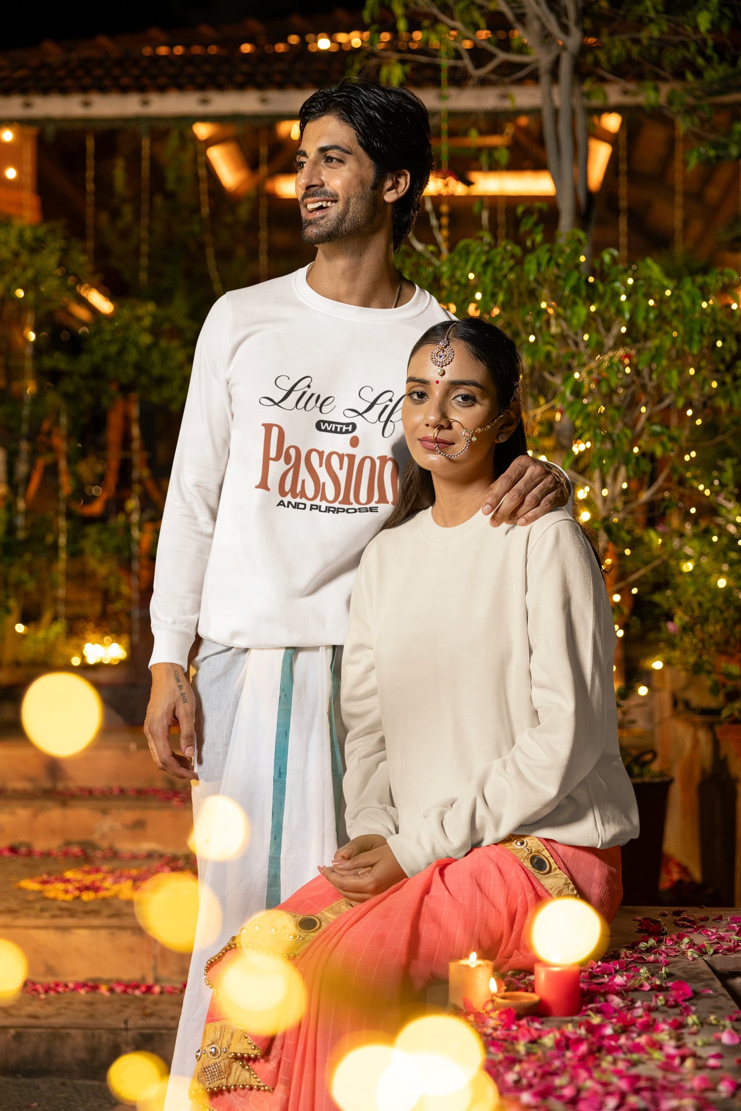 Man and woman standing together with decorative lights and flowers in the background