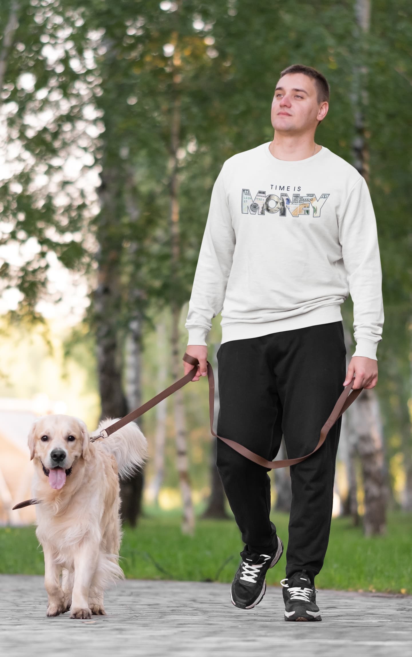Man walking a dog on a leash in a park with trees in the background