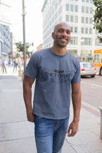 Man wearing a blue t-shirt with text standing on a city street.