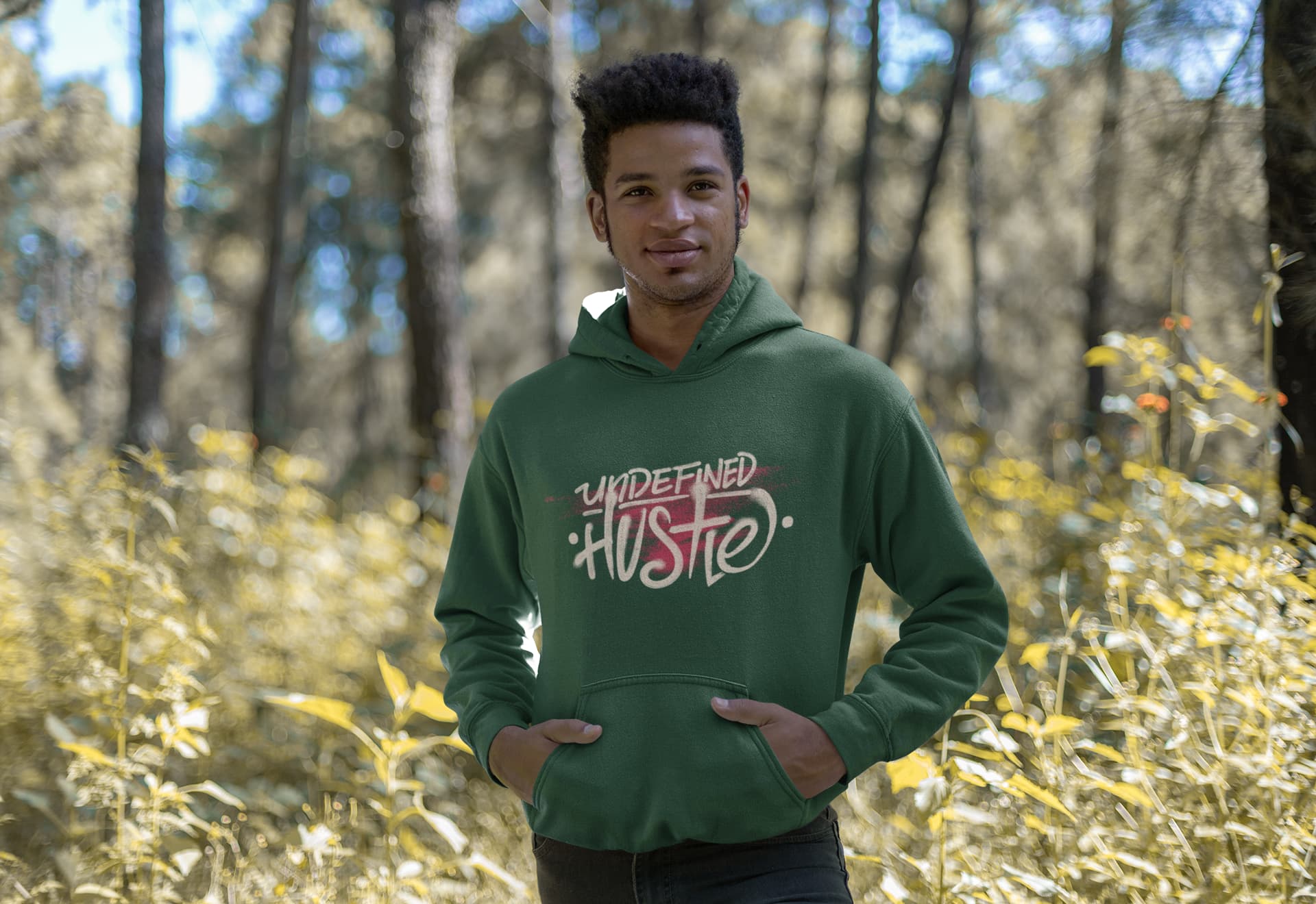 Person wearing a green hoodie with 'Undefined Hustle' text in a forest setting