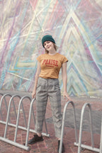 Person wearing a 'PRAISE' t-shirt in front of a colorful geometric mural.
