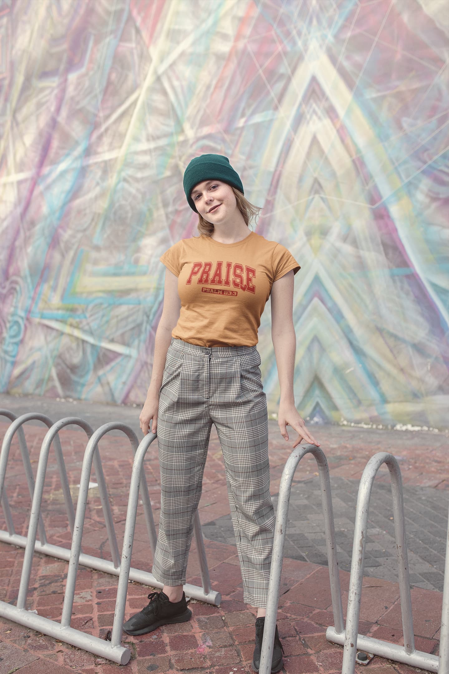Person wearing a 'PRAISE' t-shirt in front of a colorful geometric mural.