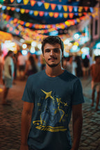Man wearing a blue t-shirt with a graphic design in a festive outdoor setting with colorful lights and people.