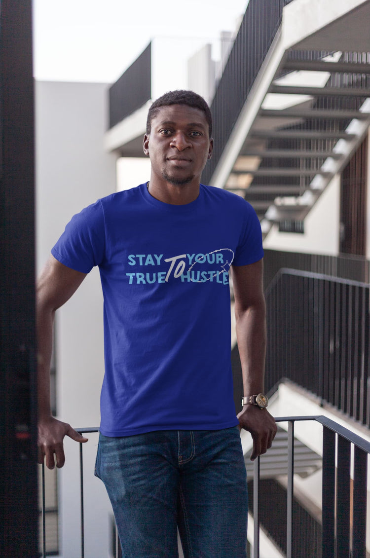 Man wearing a blue t-shirt with text standing outdoors.