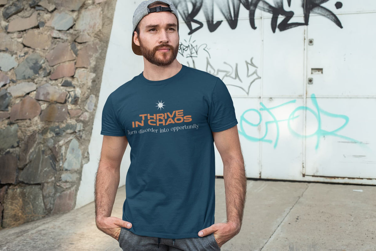 Man wearing a blue t-shirt with text standing against a graffiti-covered wall.