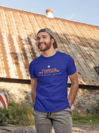 Man wearing a blue t-shirt with 'Thrive in Chaos' text standing in front of a rustic building.