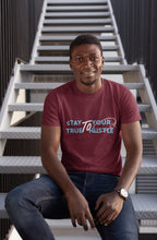 Man wearing a maroon t-shirt with text sitting on stairs