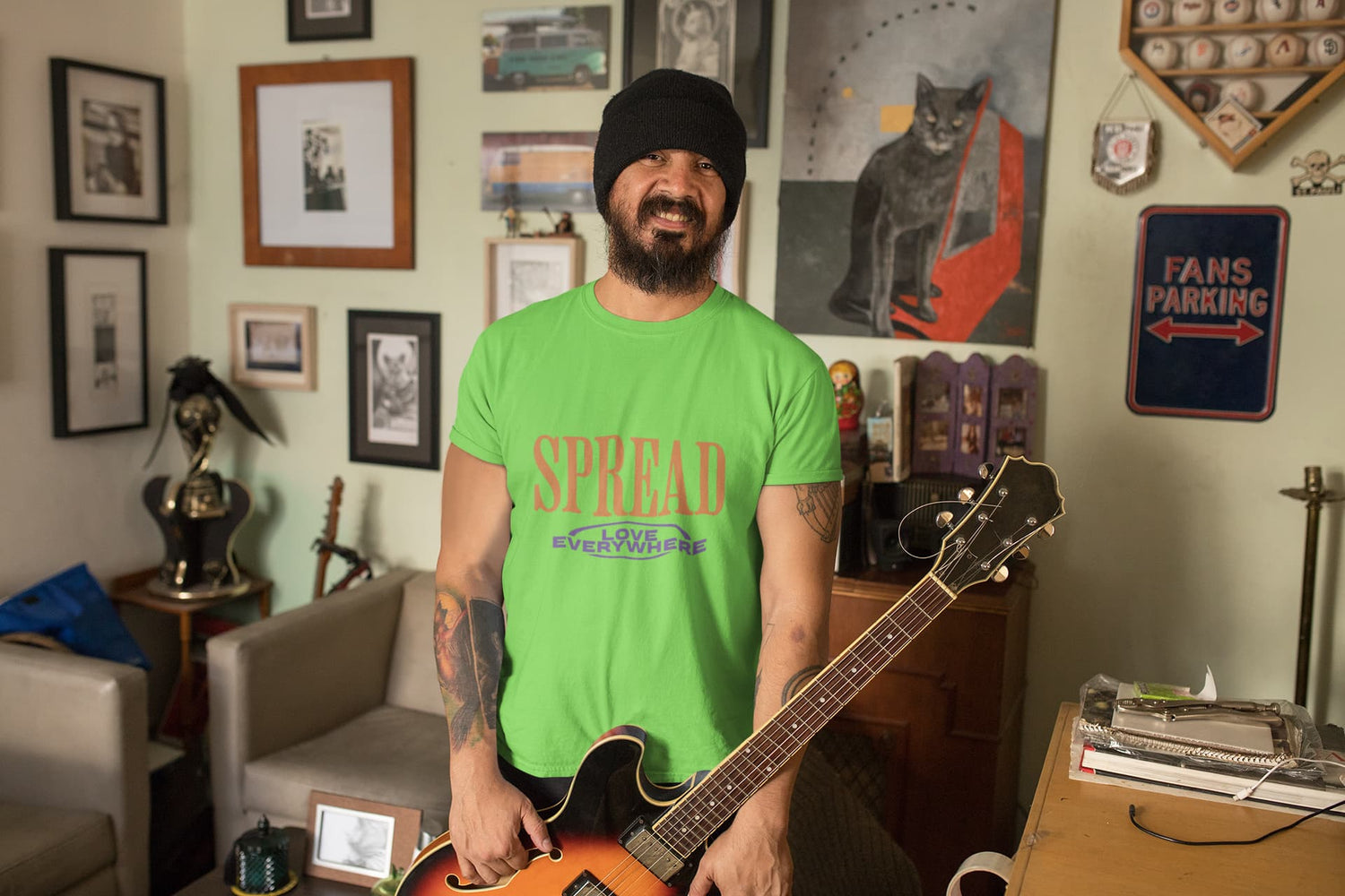 Man holding a guitar in a room with various decorations on the walls.