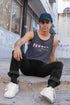 Person wearing a tank top with text, sitting on steps in an urban setting.