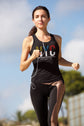 Woman running outdoors wearing a black tank top with colorful text and leggings.