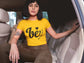Person wearing a yellow t-shirt with text, sitting inside a vehicle.